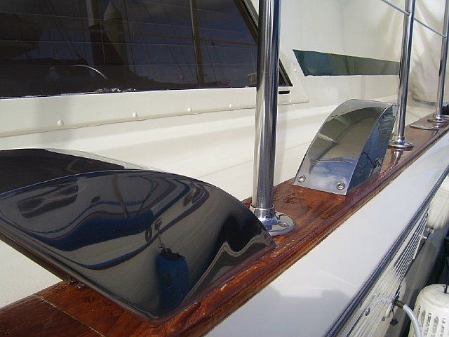 Shiny metal and wood details on a boat deck. Chrome posts and curved metal features set on a varnished wooden rail.