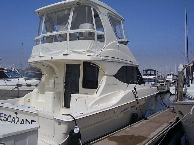 White motor yacht docked at a marina on a sunny day. 