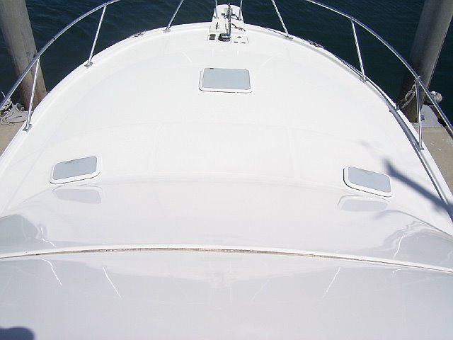 A white boat is docked at a dock in the water.