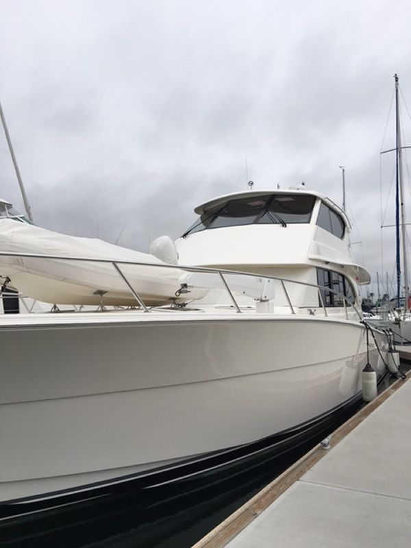 White motor yacht docked at a marina on an overcast day.