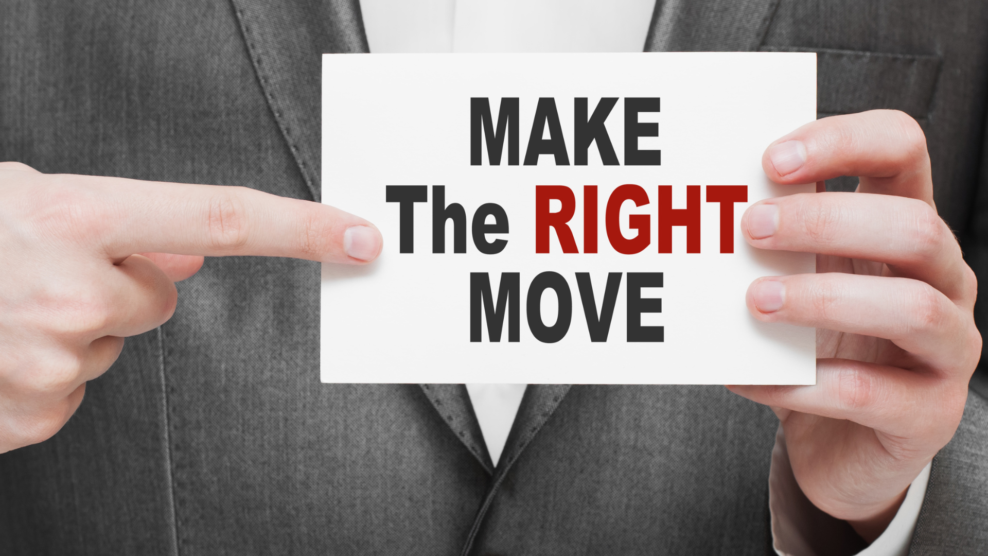 Person in a suit holding a card that reads 