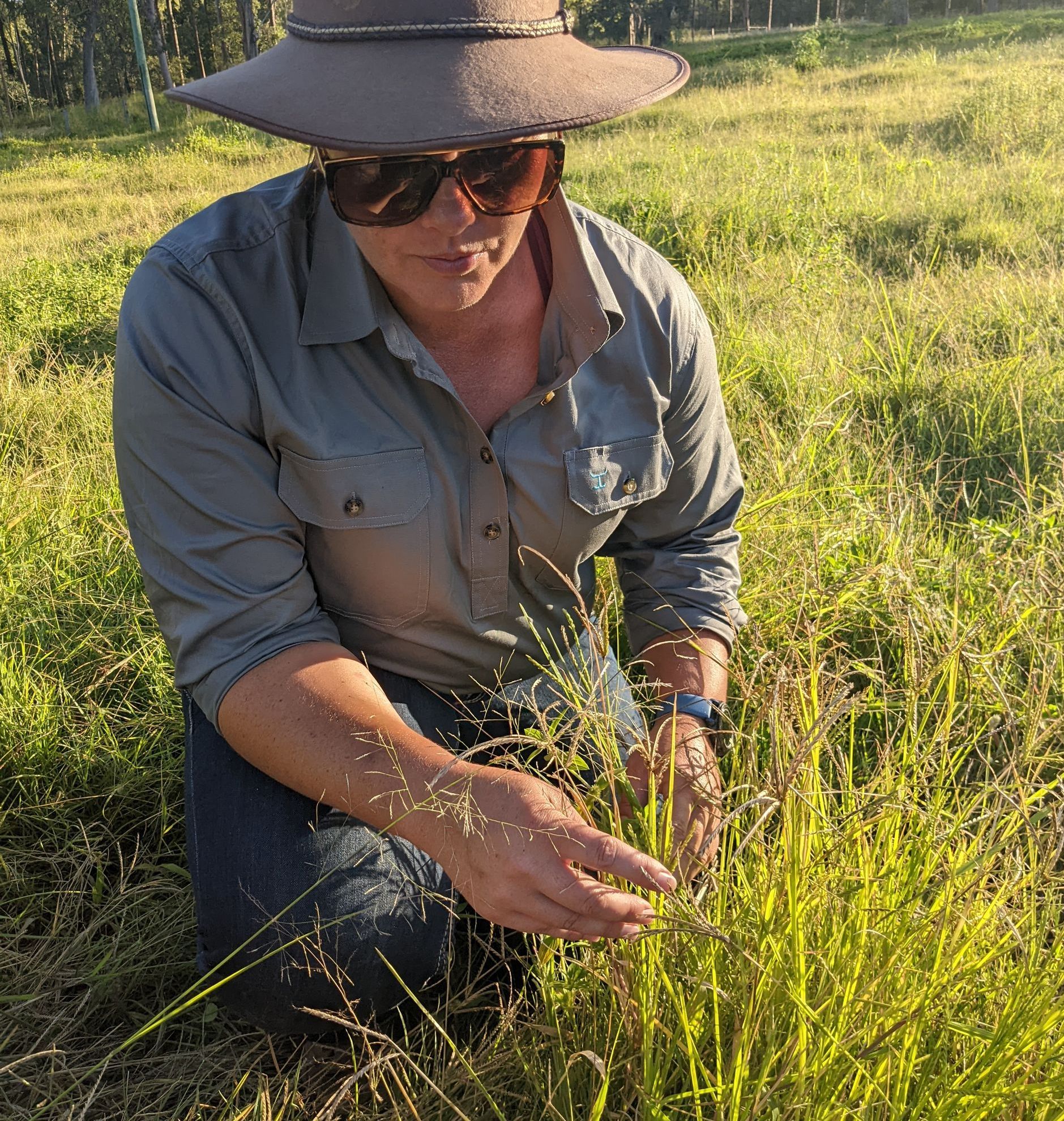 A Man is Kneeling Down in a Field Writing on a Clipboard — 2K Pasture Management and Consulting In Junction View, QLD