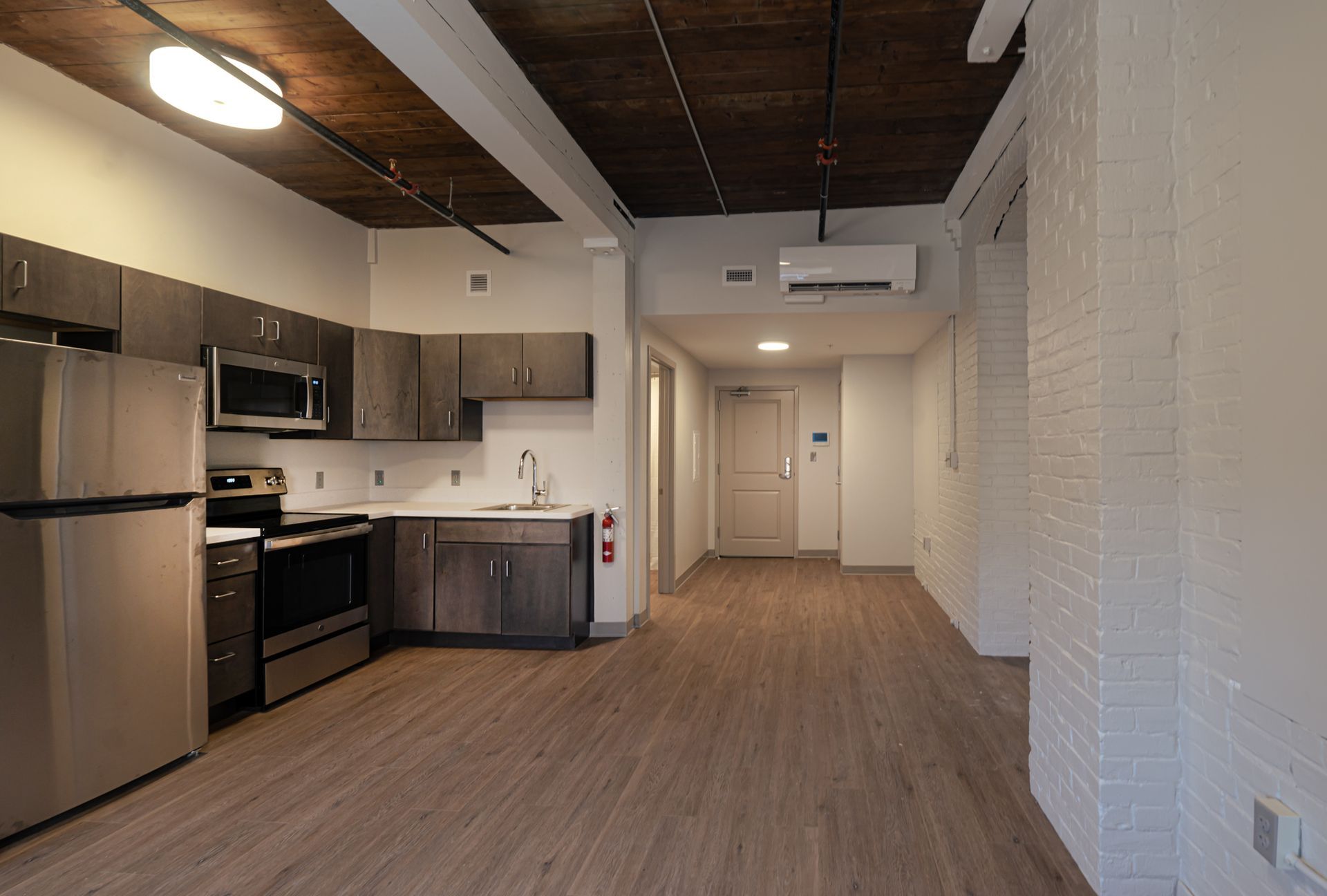 Modern kitchen and hallway in a loft apartment with stainless steel appliances and wood floors