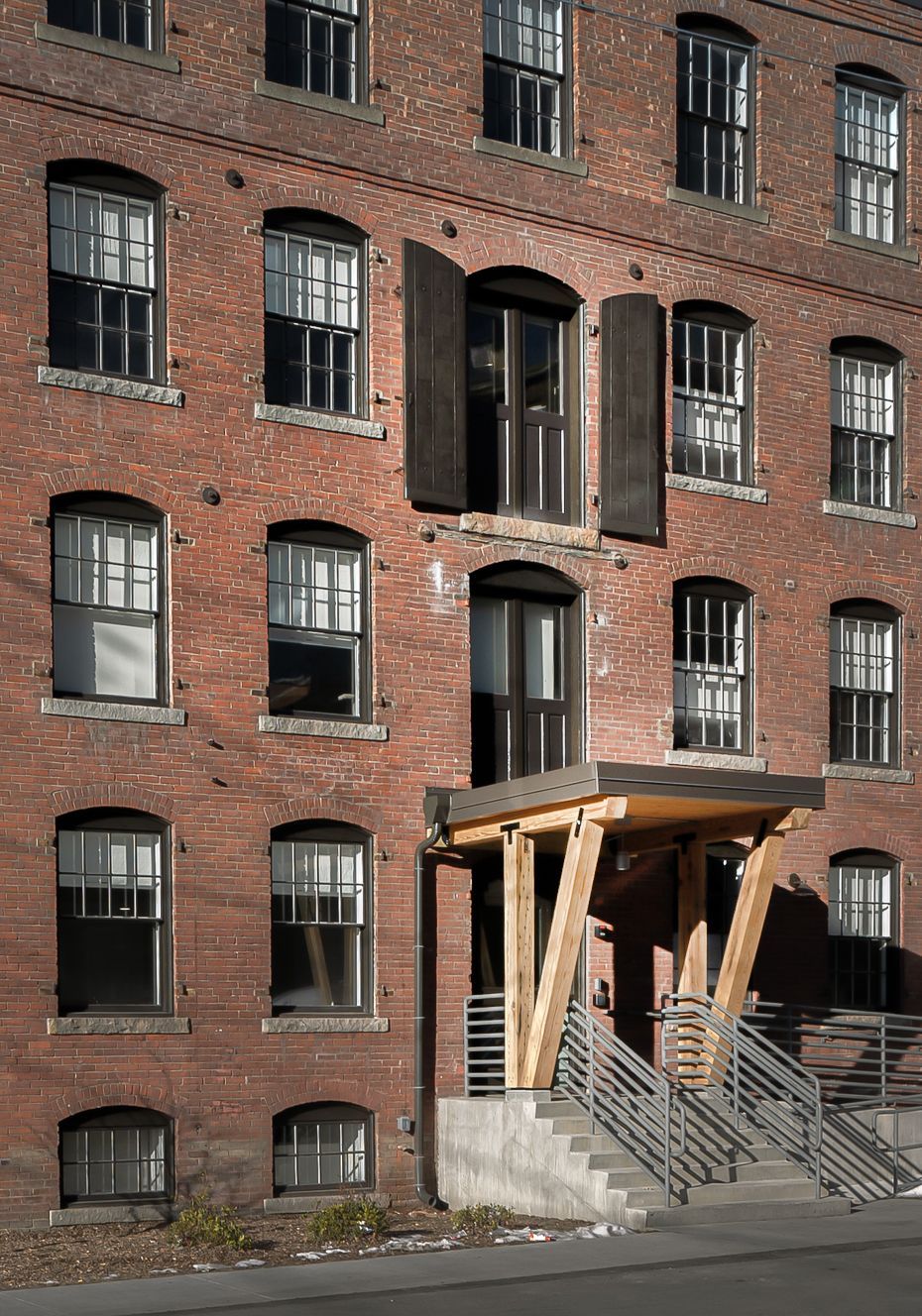 Brick apartment building entrance with wooden canopy and stairway