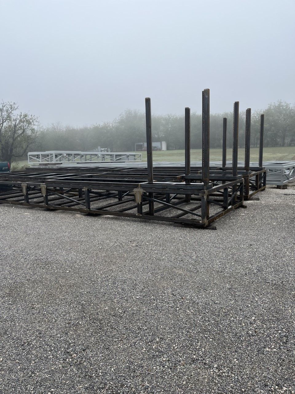 A row of metal frames are sitting on top of a gravel lot.