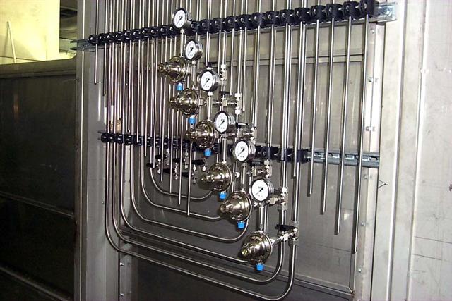 A bunch of pipes and valves are hanging on a wall.