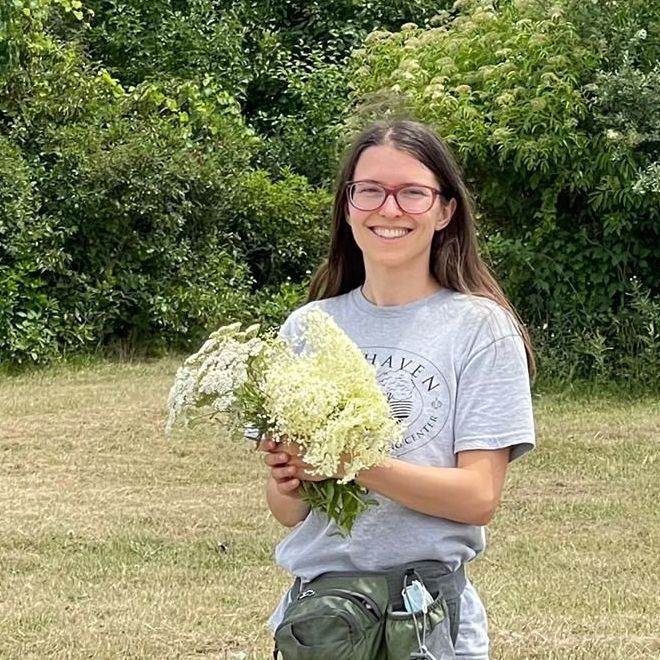 A woman is holding a bouquet of white flowers in a field.