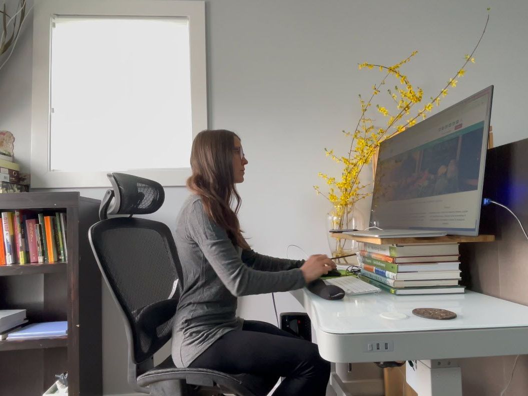 A woman is sitting at a desk in front of a computer.
