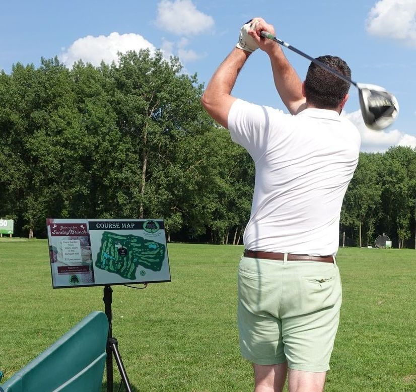 A man is swinging a golf club on a golf course