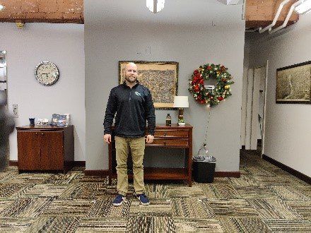 A man is standing in a room with a clock on the wall.