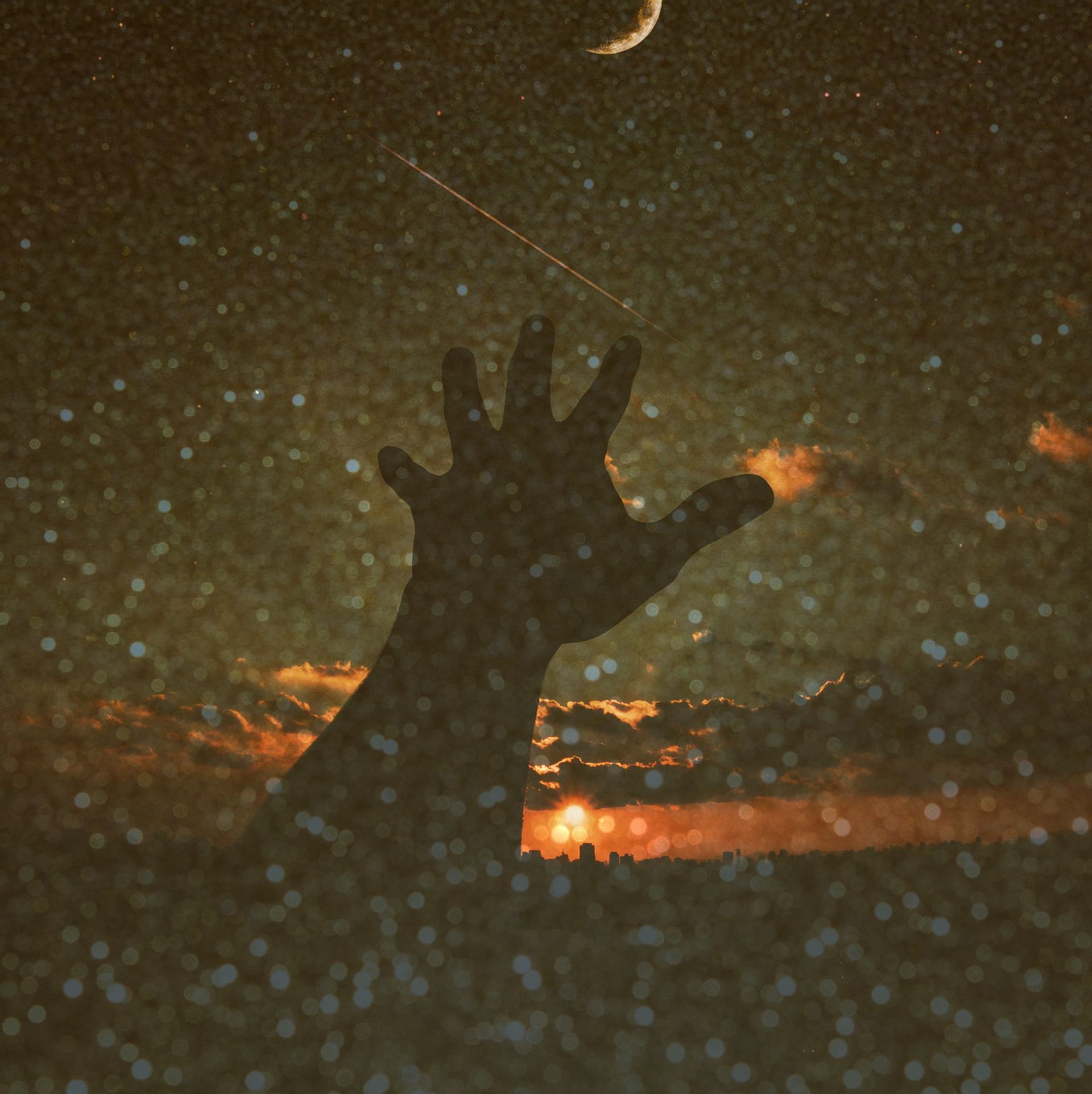 A silhouette of a hand reaching up into the night sky