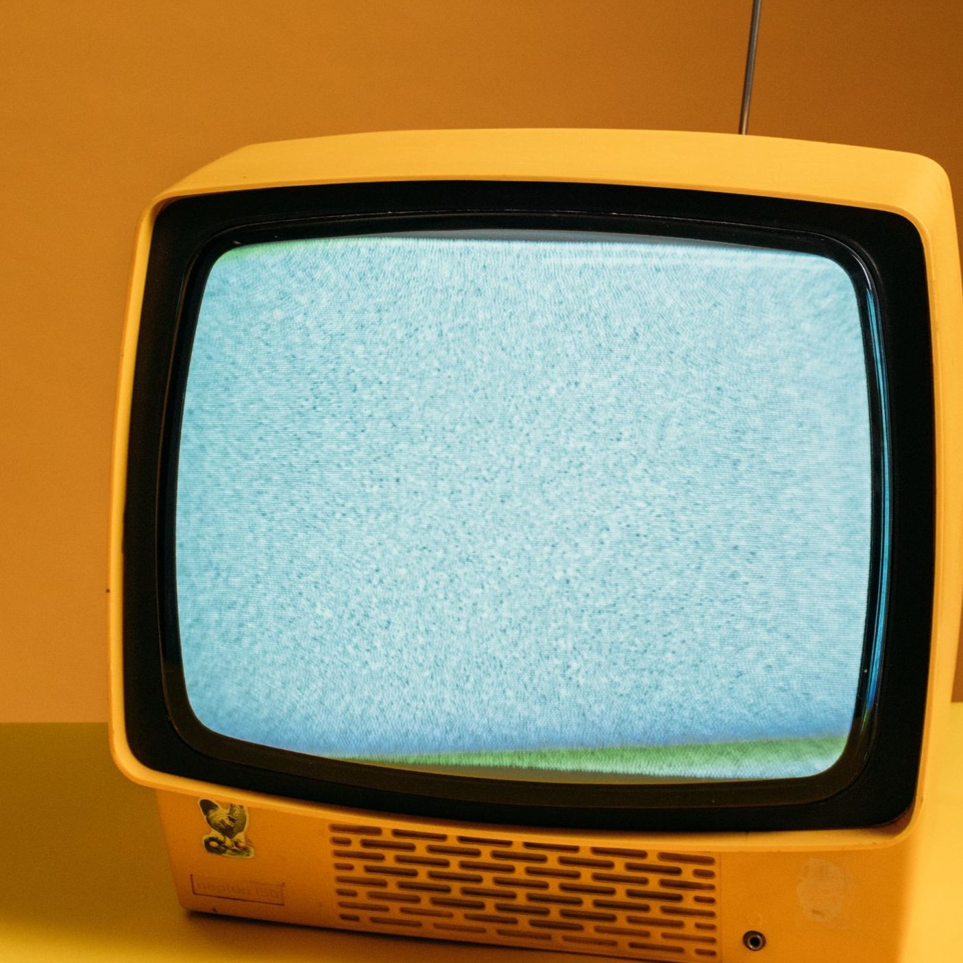 A yellow television shows a static screen