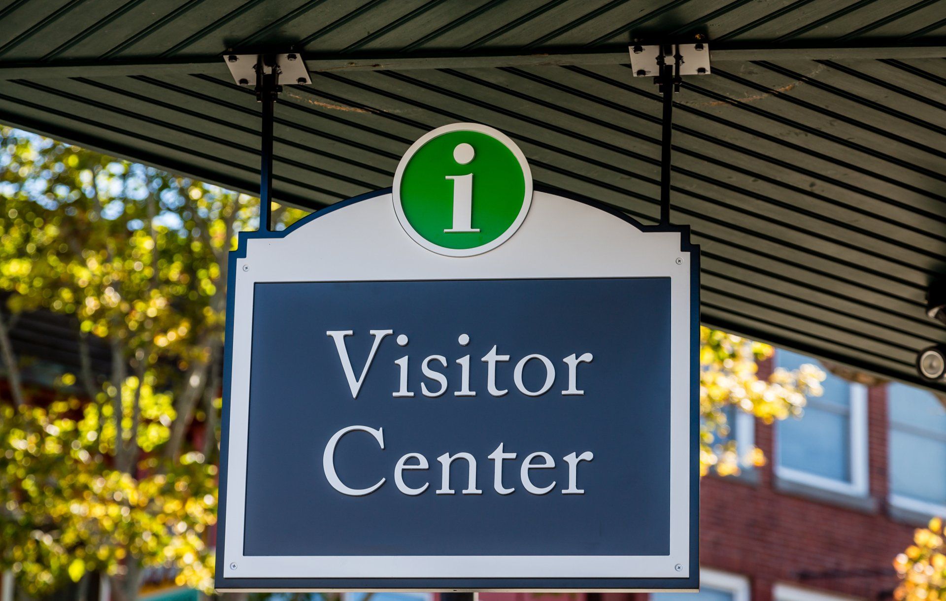 A visitor center sign is hanging from the ceiling of a building.