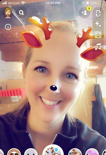 A woman is wearing a reindeer face mask on her phone.