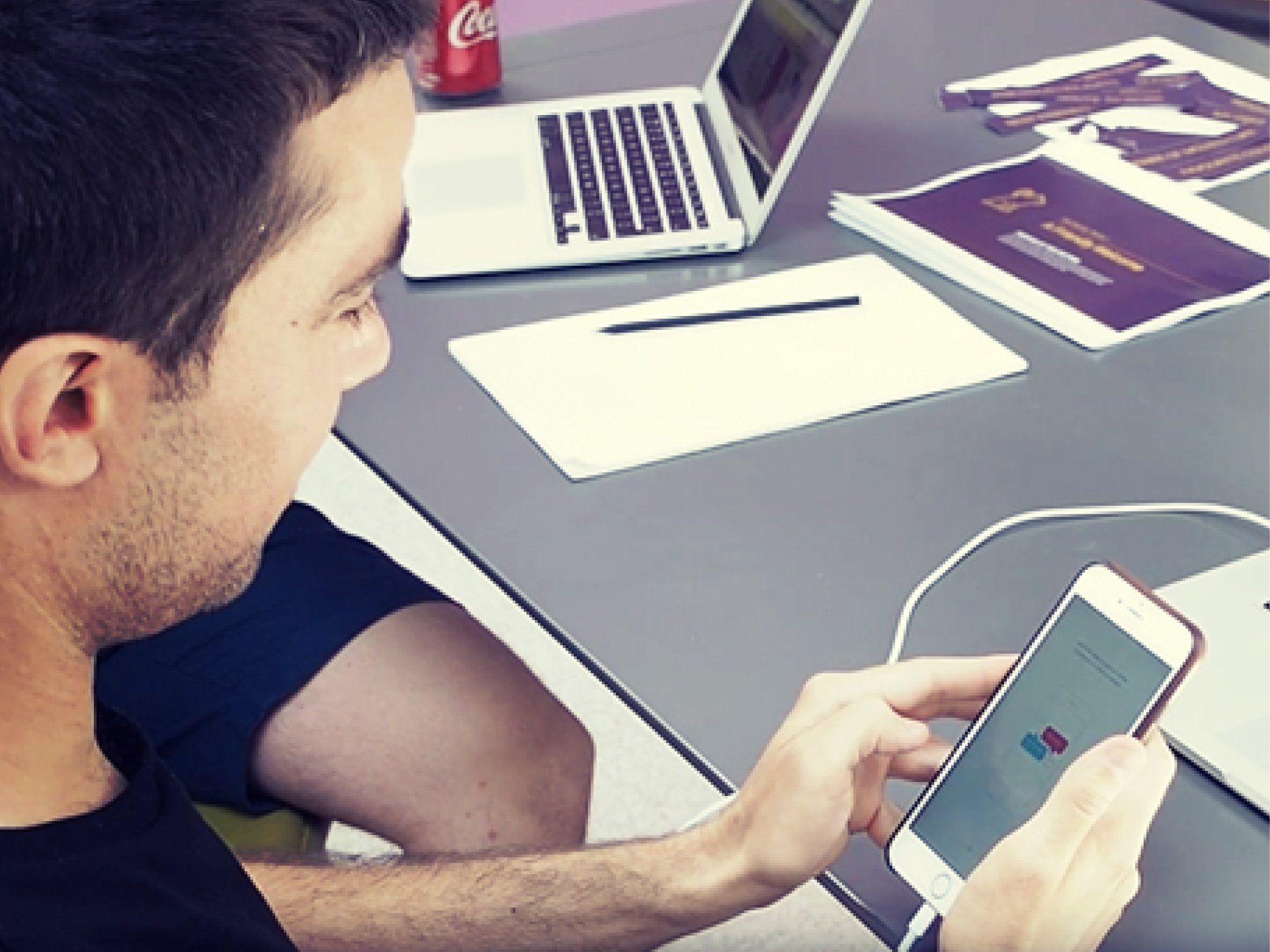 a man is sitting at a table using a cell phone