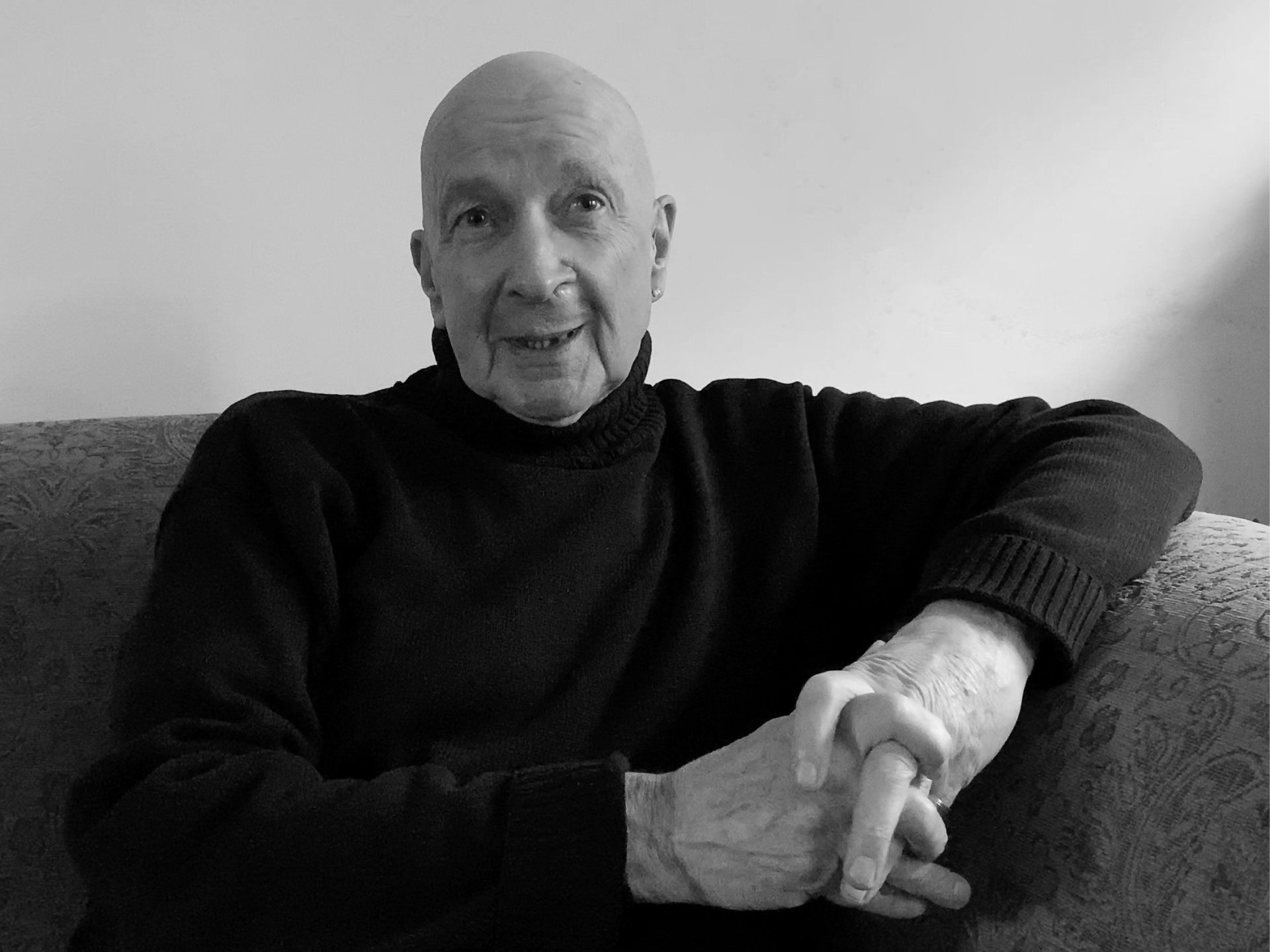 a man in a black sweater is sitting on a couch