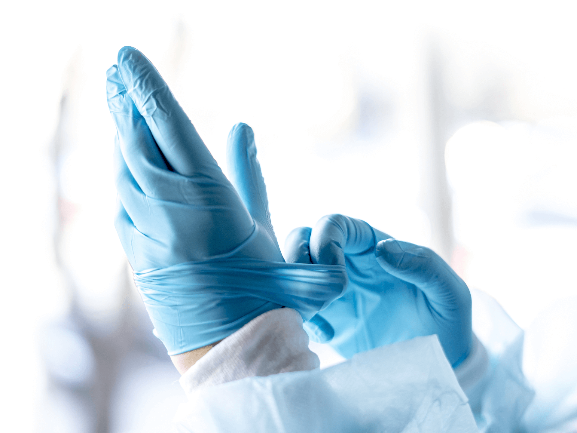 A person is putting on a pair of blue gloves.