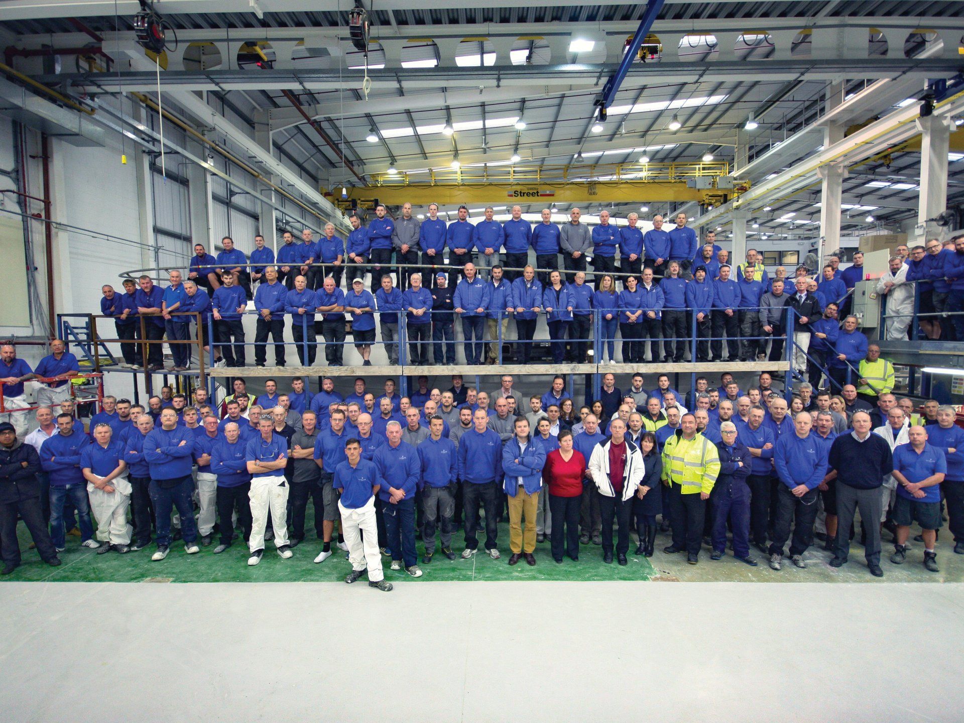 A large group of people are posing for a picture in a factory.