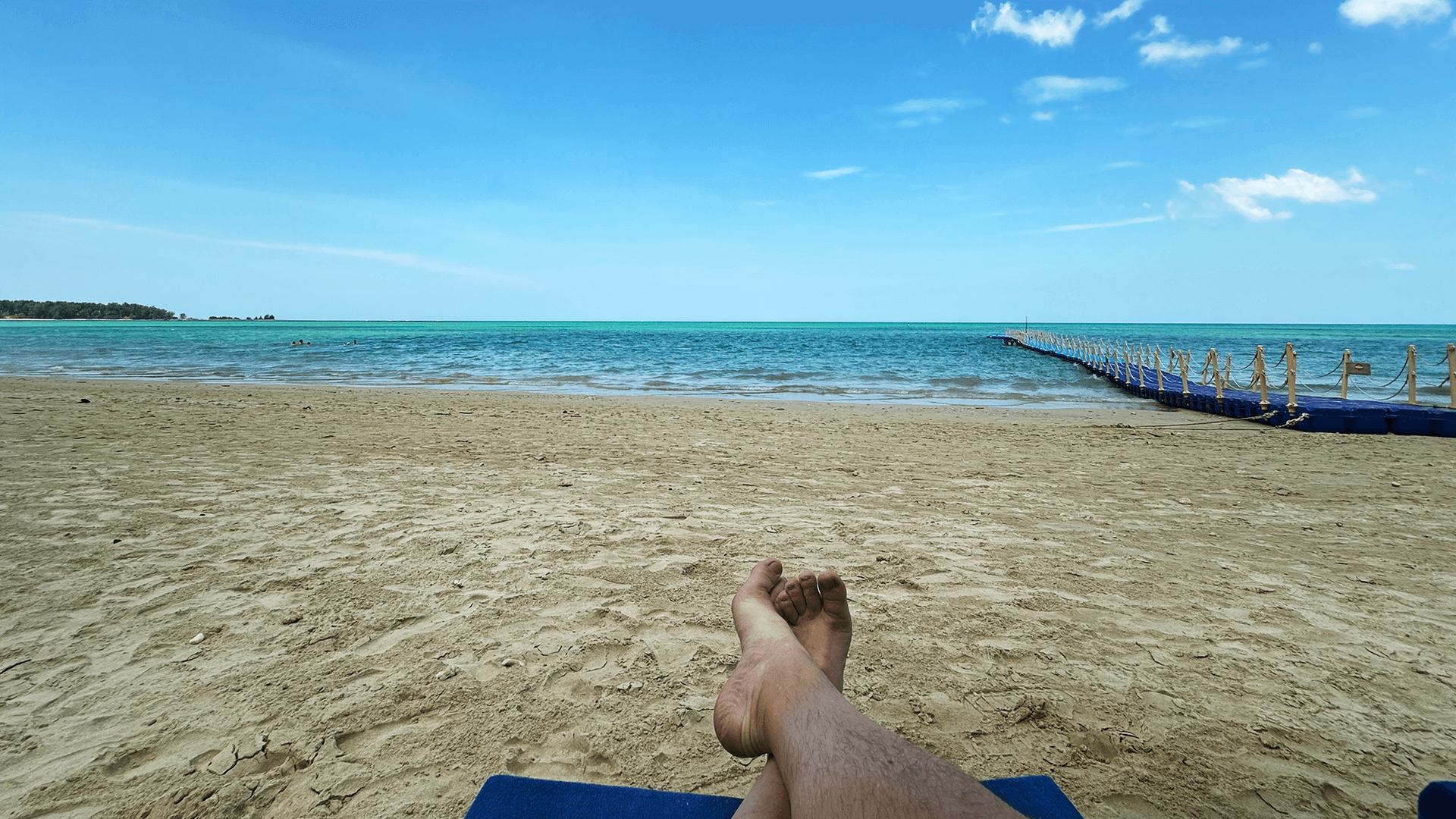 A person is laying on a beach with their feet up.