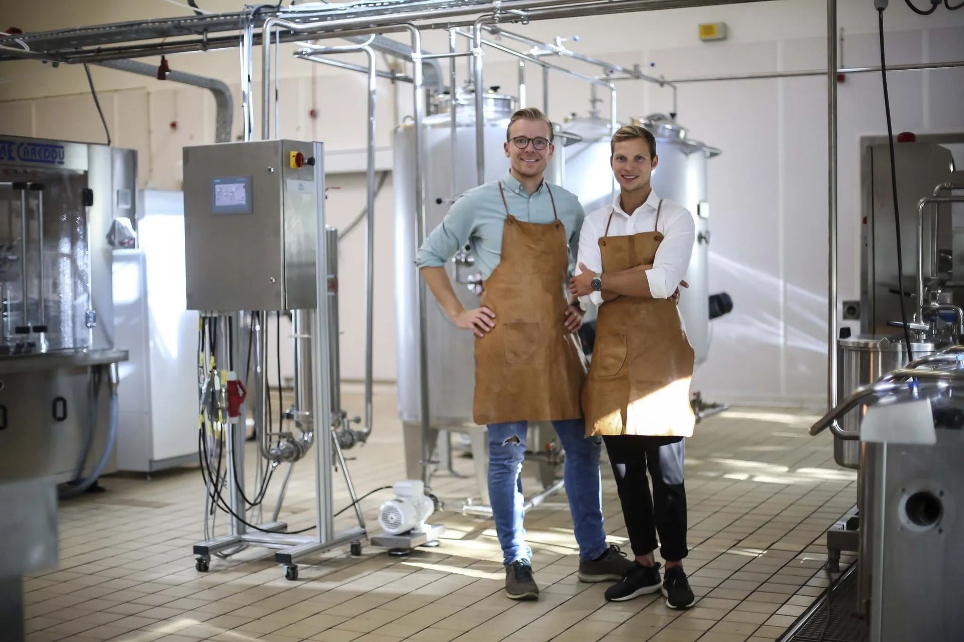 two men in aprons are standing next to each other in a factory .