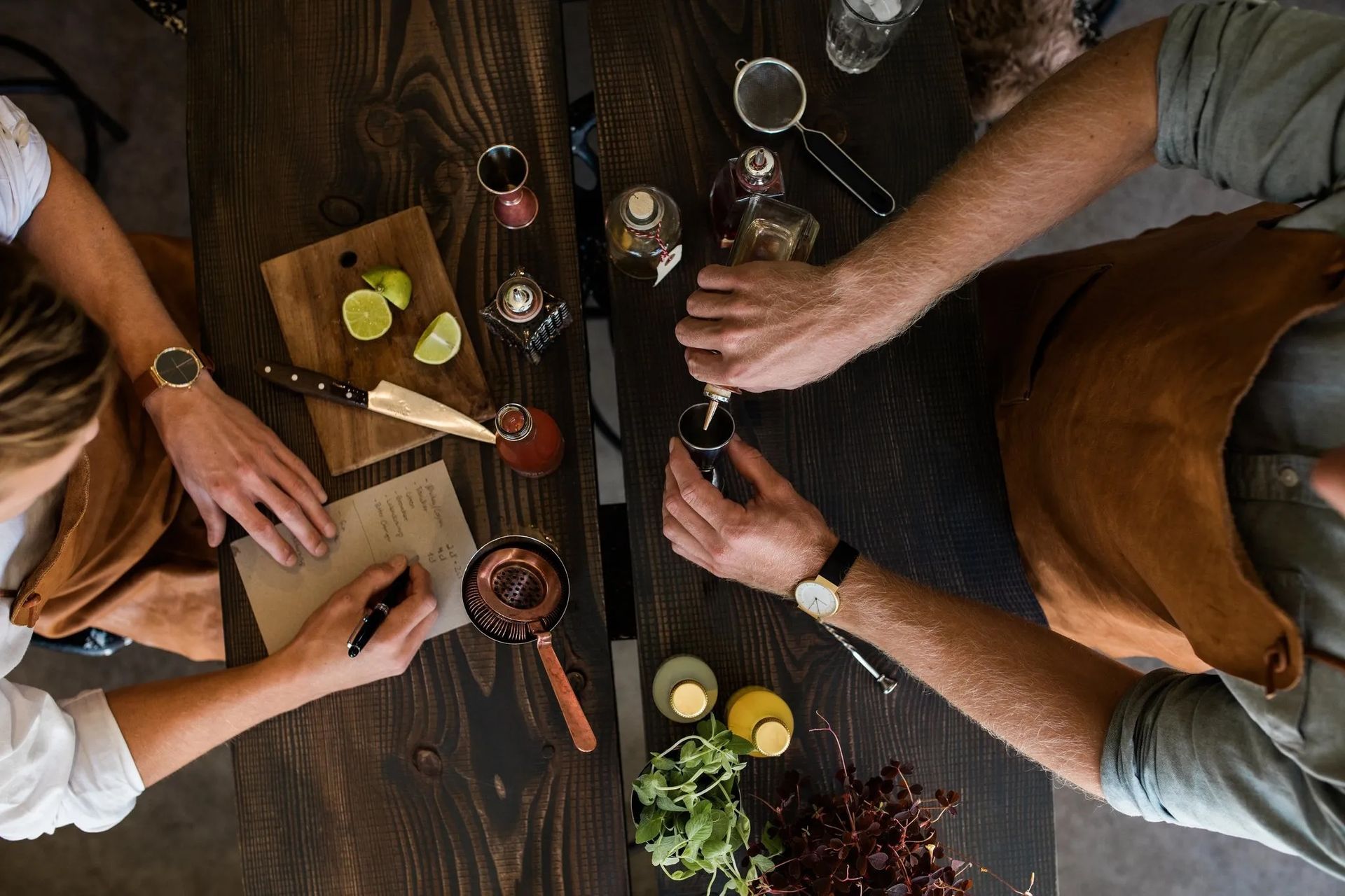 a man and a woman are sitting at a table making a drink .