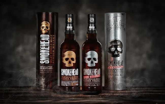 three bottles of smokehead whiskey are sitting on a wooden table .