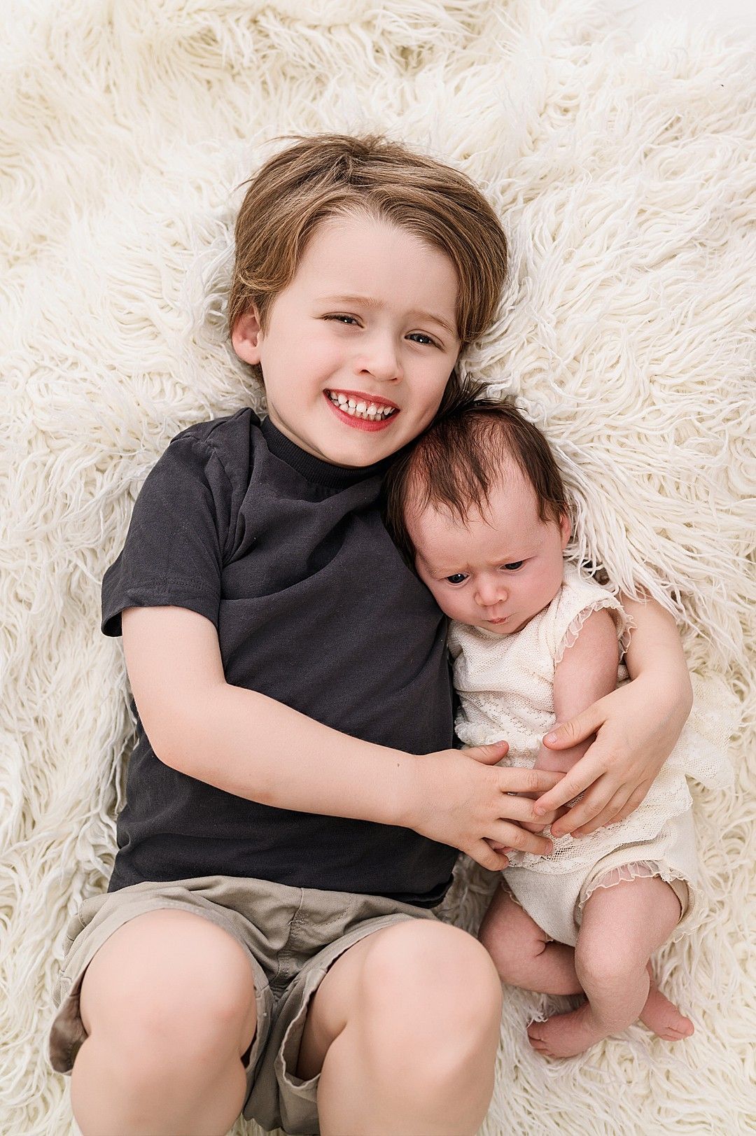 Big brother cuddling her newborn sibling at a professional baby photography session in Dublin
