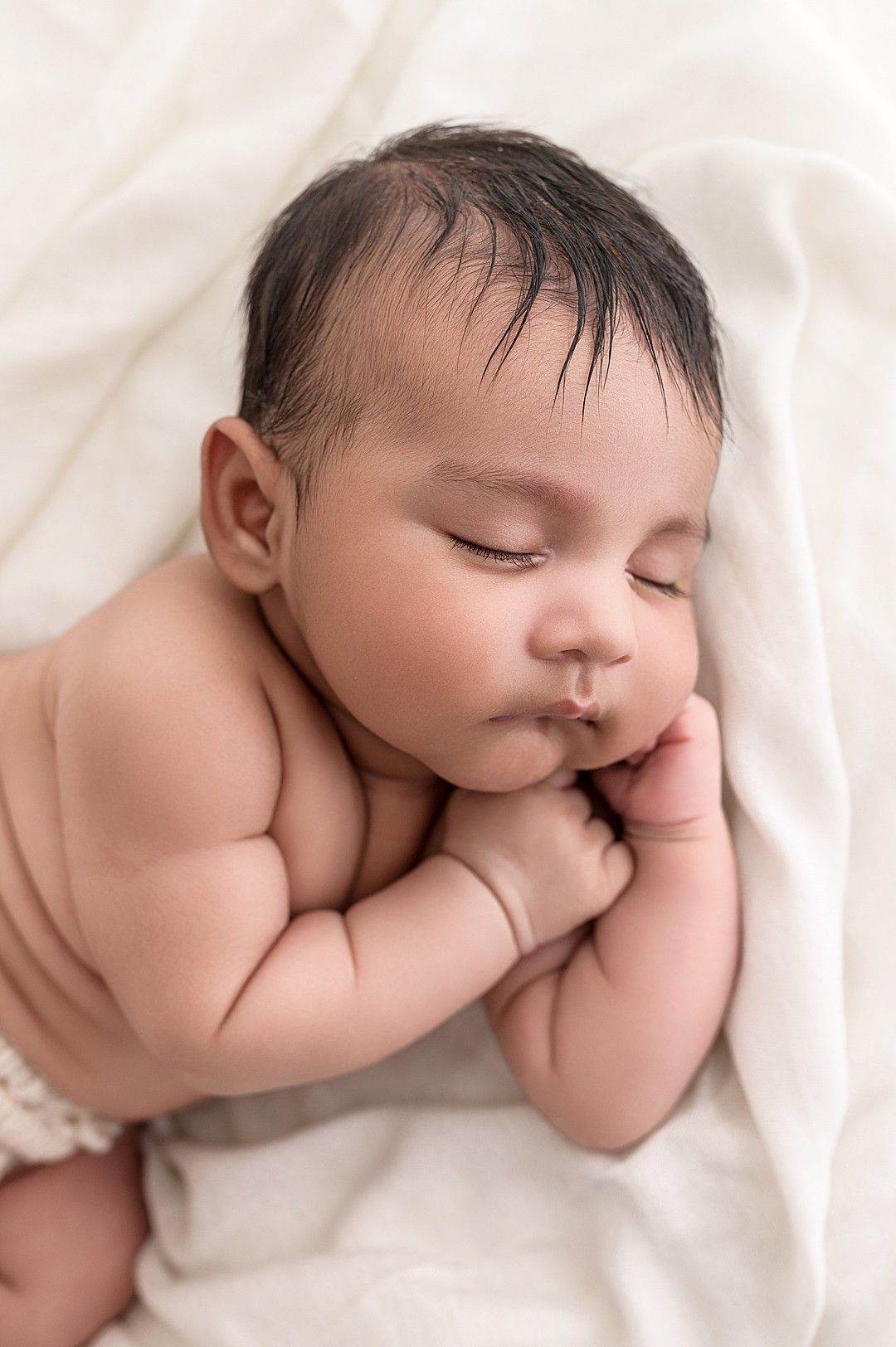 Sleeping newborn baby photographed on a soft cream blanket during a calm, baby-led newborn photography session at Linda Clarke Photography's Dublin studio.