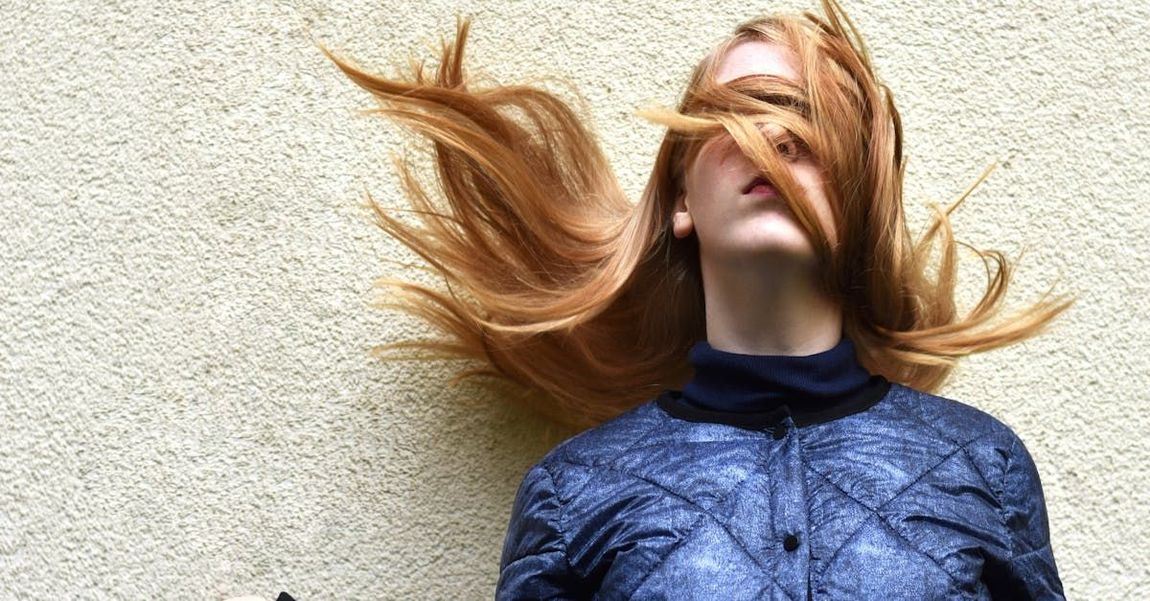 A woman is laying on the floor with her hair blowing in the wind.