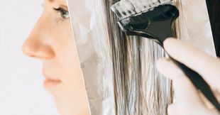 A woman is getting her hair dyed by a hairdresser.