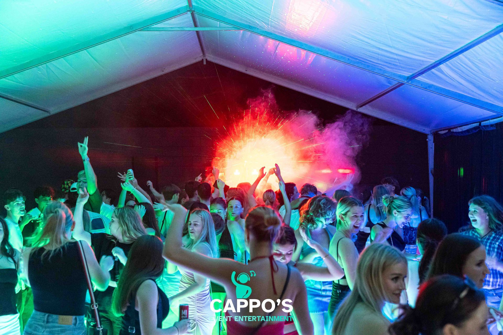 a group of people are dancing under a tent at a party .