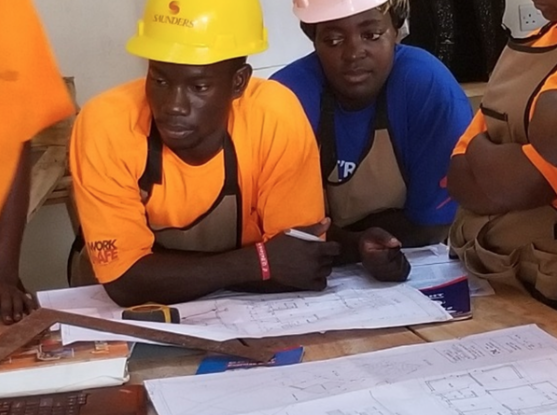 a group of men wearing hard hats and looking at blueprints