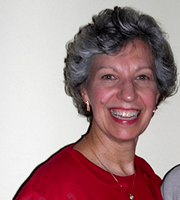 Gray-haired woman in red shirt grinning.