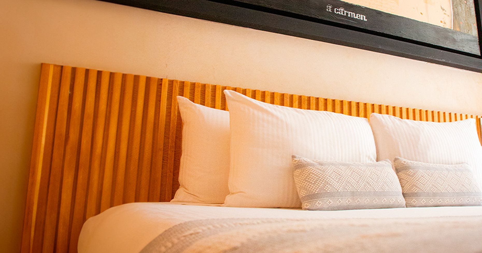 Bed with a wooden headboard, white pillows, and decorative accent pillows.