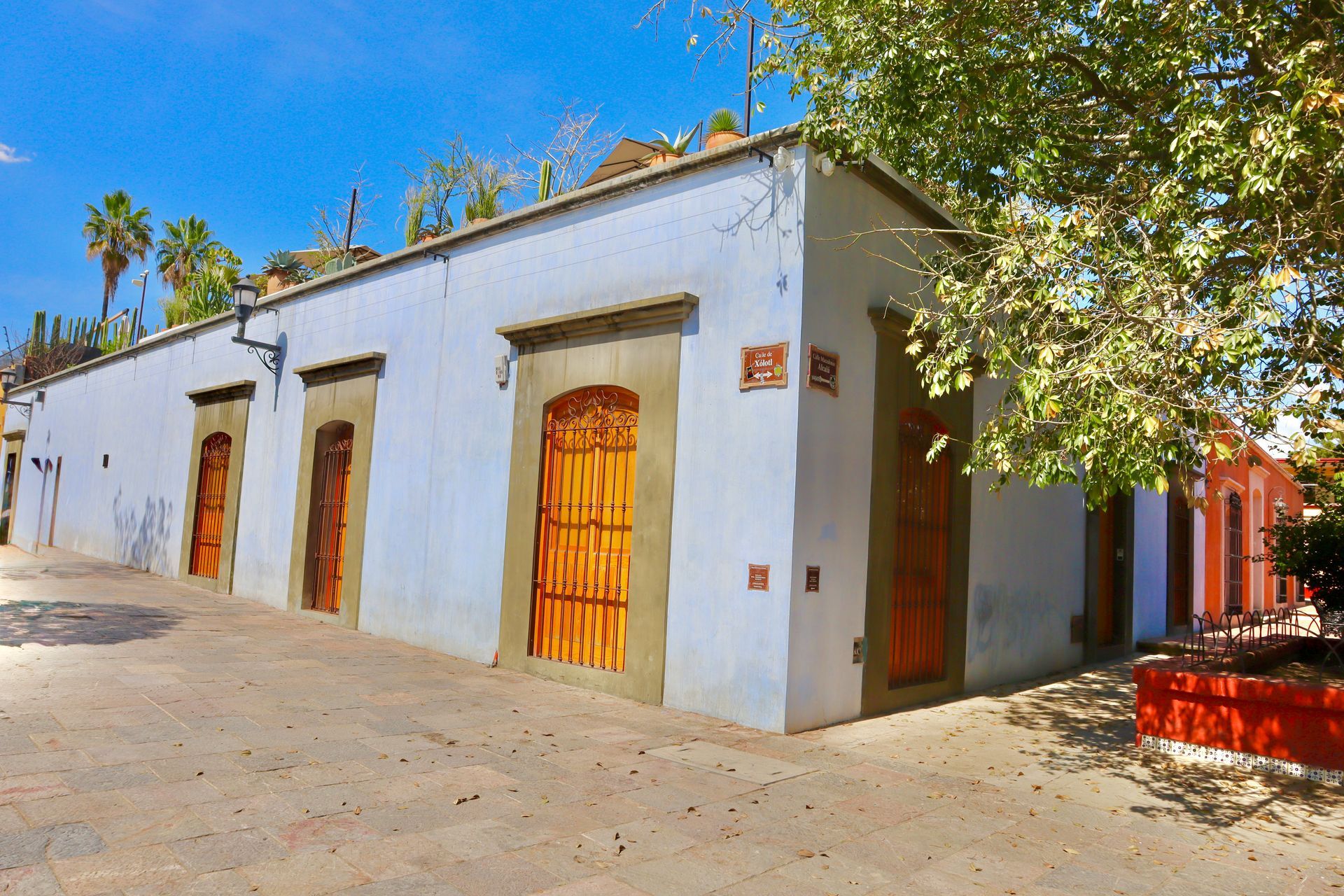 Bathroom with colorful patterned tiles, two white sinks, and a large mirror. Bright orange door on the right.