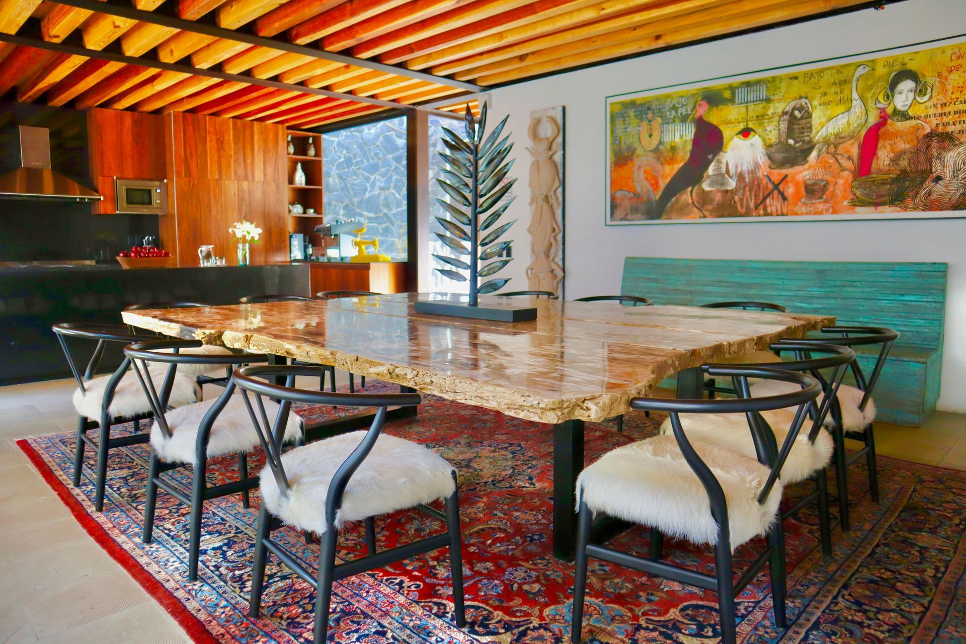 Shop display of colorful woven rugs, hanging and on tables. Red, orange, blue, and yellow patterns.