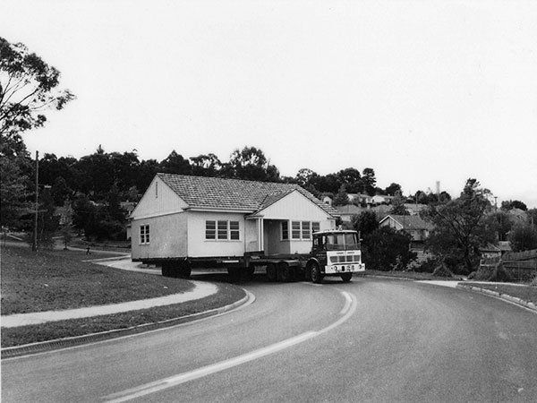truck pulling vintage home up the road