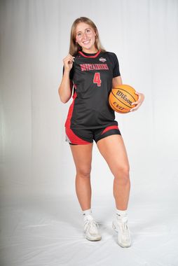 A woman in a black shirt and red shorts is holding a basketball.