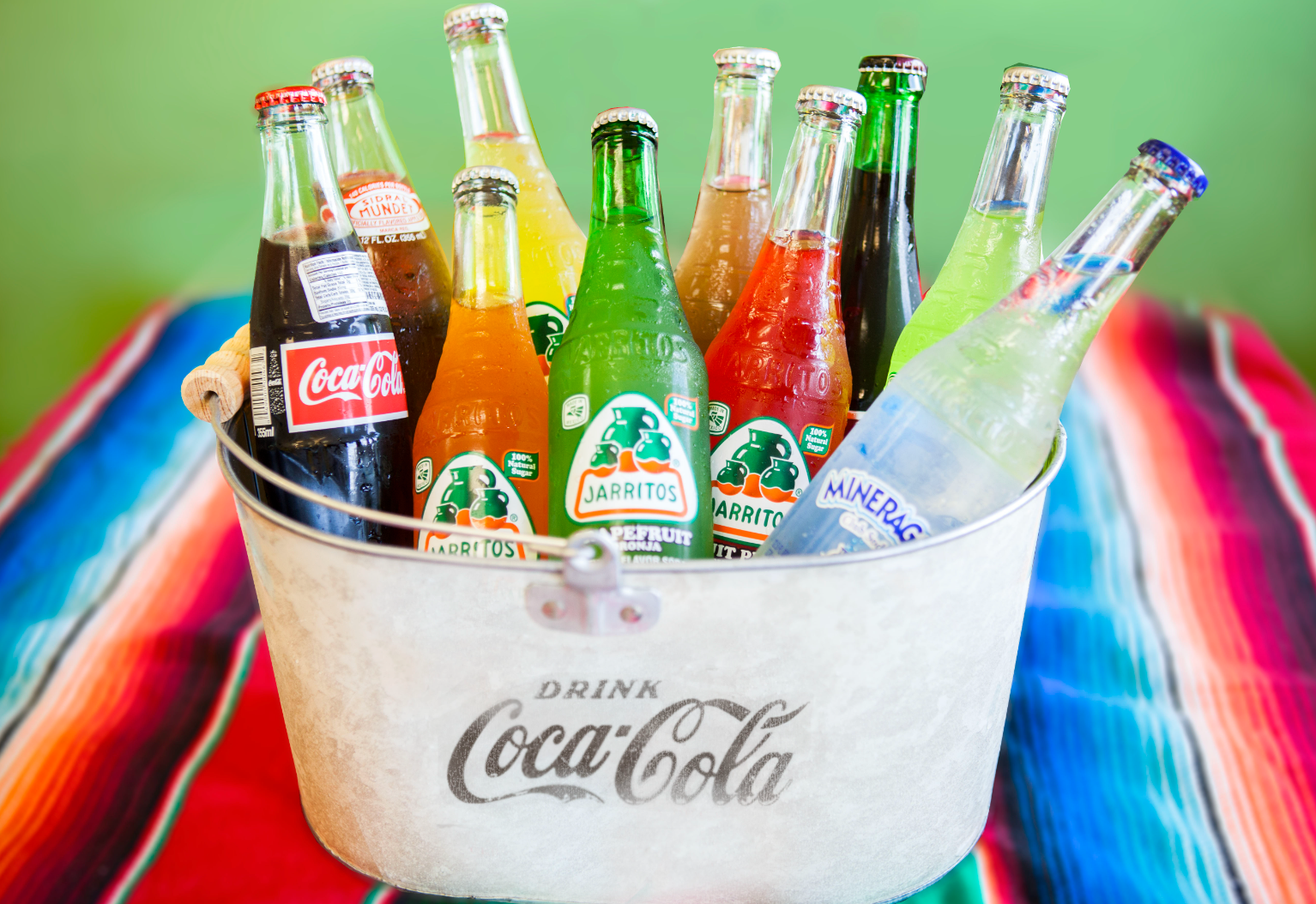 A bucket filled with coca cola bottles on a table