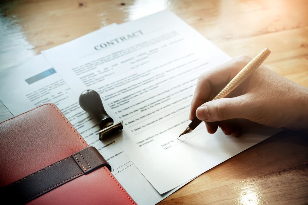 A Person Is Writing On A Piece Of Paper With A Pen — SJP Law In Maroochydore, QLD