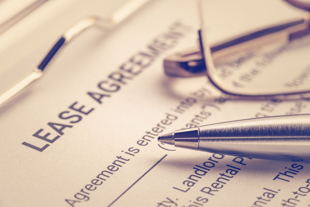 A Pen And Glasses Are On Top Of A Lease Agreement — SJP Law In Maroochydore, QLD
