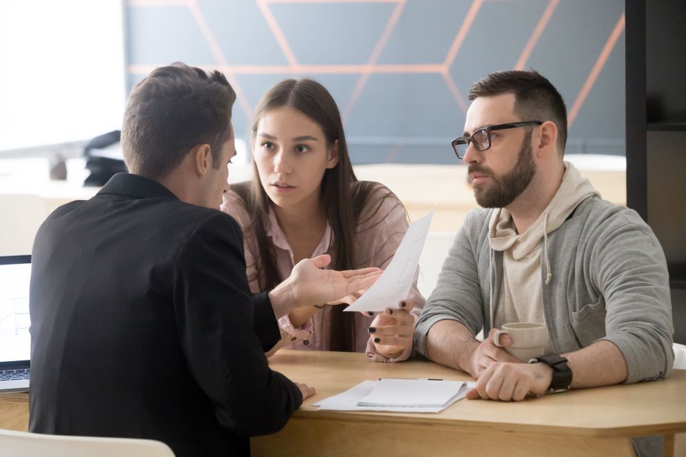 A Man And A Woman Are Sitting At A Table Talking To Each Other — SJP Law In Maroochydore, QLD