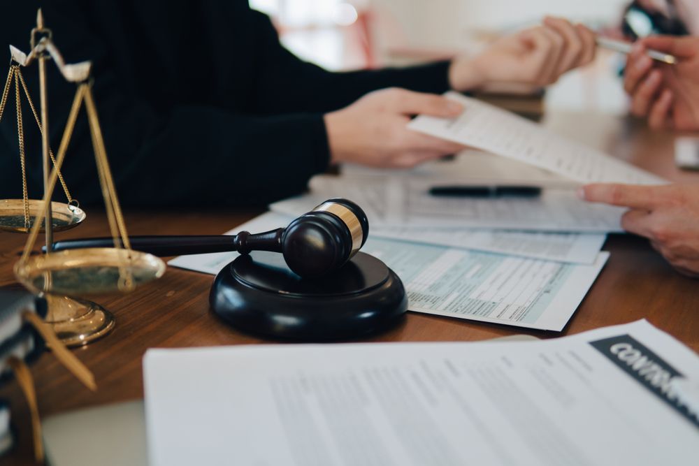 A Group Of People Are Sitting At A Table With Papers — SJP Law In Maroochydore, QLD