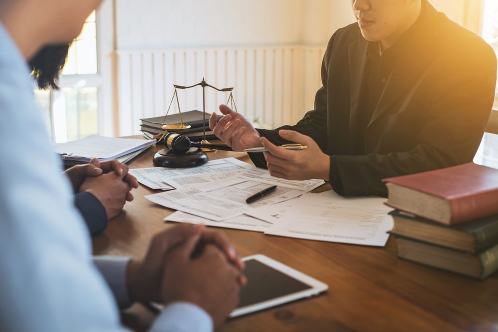 A Group Of People Are Sitting At A Table Talking To Each Other — SJP Law In Palmwoods, QLD