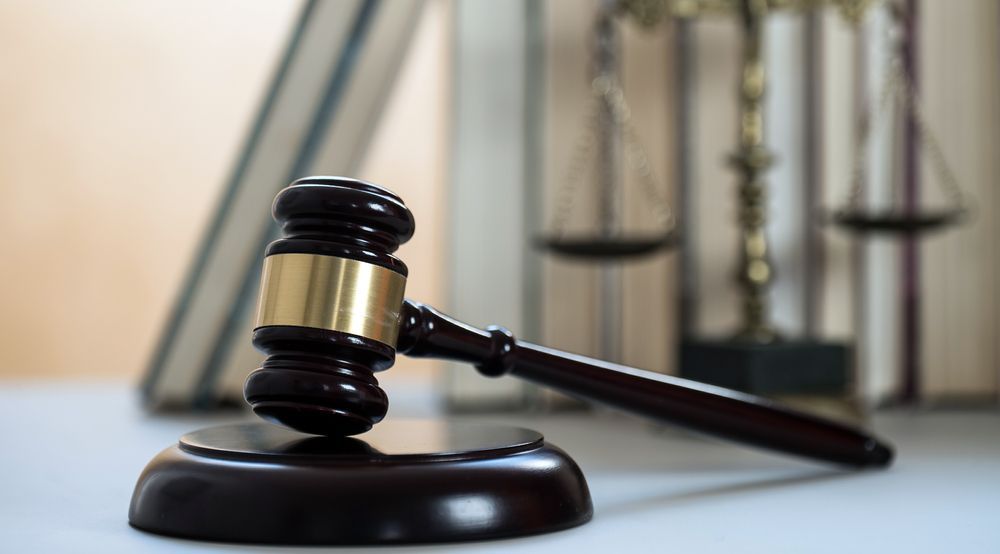 A Wooden Judge's Gavel Is Sitting On A Table In Front Of A Scale Of Justice — SJP Law In Maroochydore, QLD