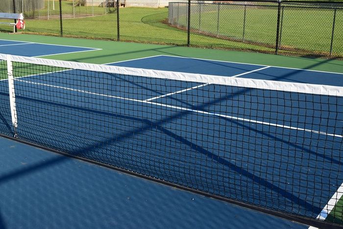 A blue tennis court with a white net