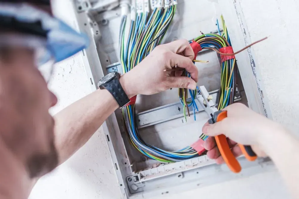 Electrician Working on Wires in an Electrical Panel, Using Pliers — KACE Electrical Solutions In Warwick, QLD