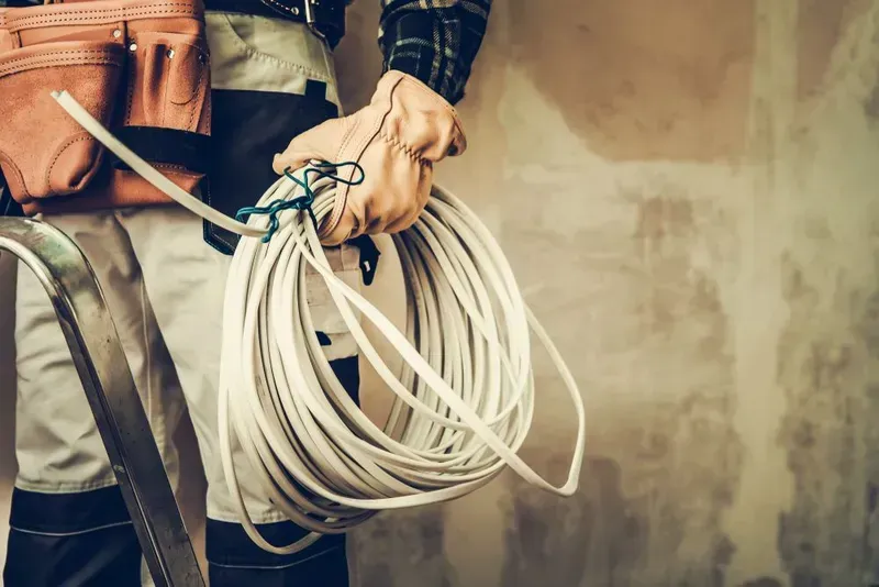 Electrician Holding Coiled White Electrical Wire — KACE Electrical Solutions In Warwick, QLD
