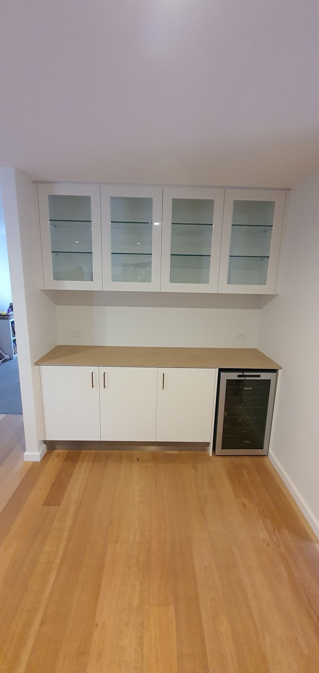An empty room with hardwood floors and white cabinets.