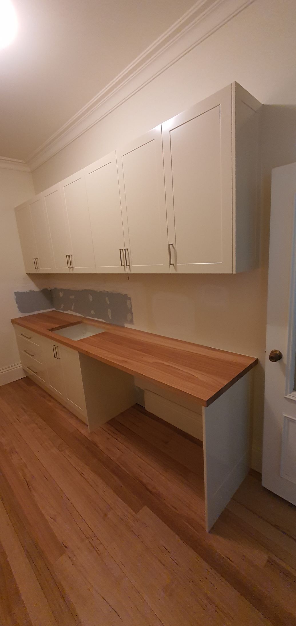 A kitchen with white cabinets and a wooden counter top.